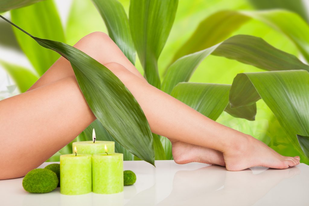 Jambes parfaitement épilées posant dans un décor vert